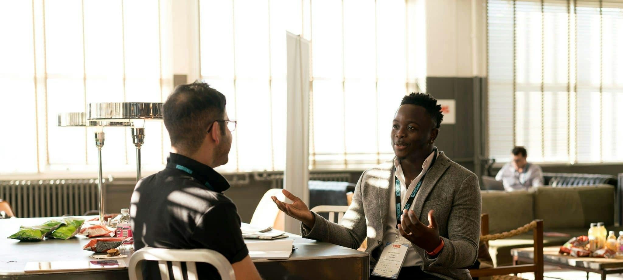 Two men having a casual discussion in a bright indoor setting, highlighting mentorship.