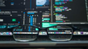 Eyeglasses reflecting computer code on a monitor, ideal for technology and programming themes.