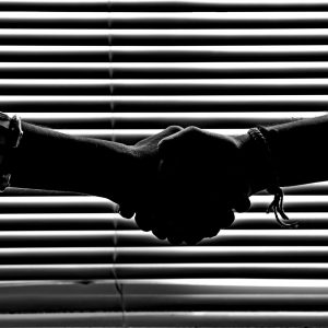 Silhouette of two people shaking hands symbolizing partnership and trust.